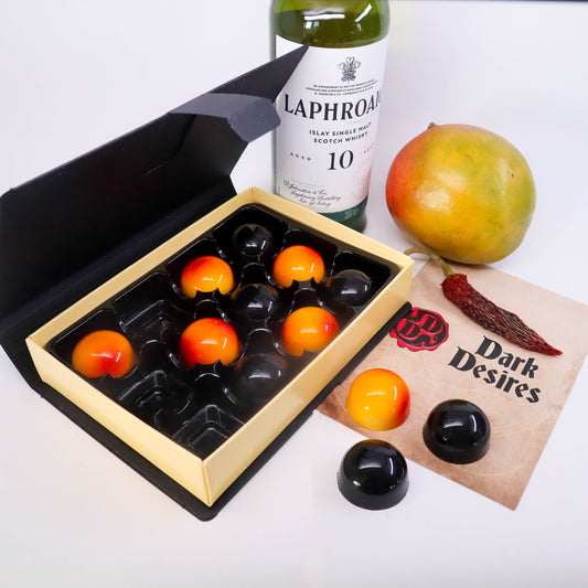 Luxury black box of handmade chocolates by dark desires, mango, chili pepper and a bottle of scotch 